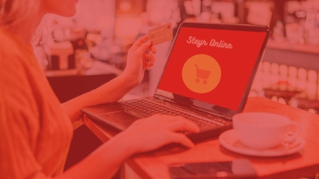 Junge Frau, die an ihrem Laptop einen online Kauf abschließt
